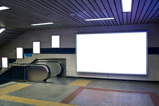 cartelera en blanco al lado de escaleras mecánicas en metro útil para tu publicidad photo