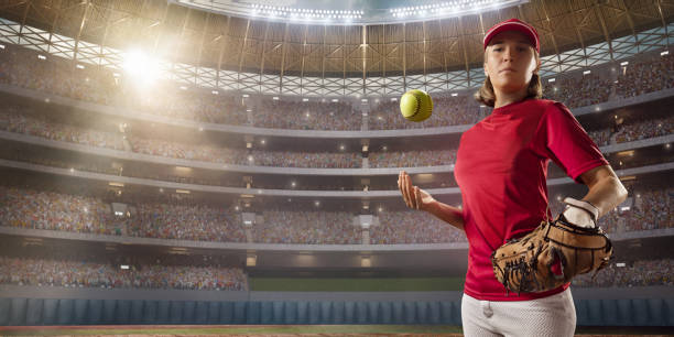 Softball female player on a professional arena. Beautiful athlete in unbranded uniform on big arena. The player throws up the ball.