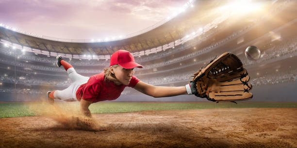 Softball female player on a professional arena Softball female player on a professional arena. Beautiful athlete in unbranded uniform on big arena. The player flies and catches the ball. softball pitcher stock pictures, royalty-free photos & images