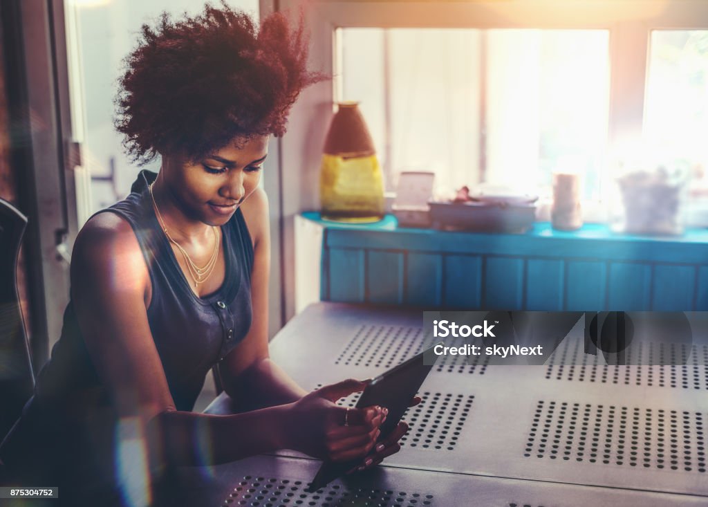 Junge Afro Frau am Tisch mit TabletPC - Lizenzfrei Tablet PC Stock-Foto