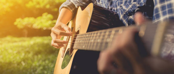 istock woman playing guitar at public park 875316152
