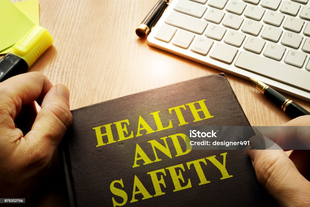 Mãos segurando documentos com segurança e saúde do título. - Foto de stock de Saúde e segurança ocupacional royalty-free