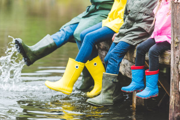 family sitting on wooden bridge partial view of family in rubber boots sitting on wooden bridge near lake Woodbridge stock pictures, royalty-free photos & images