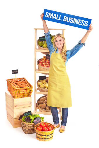 Concept of small family owned business grocery store, a young woman small business owner holding up a sign \