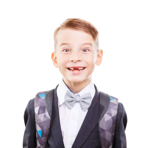 Young cute primary school student fooling around. Young cute schoolboy showing teethless smile isolated on white background