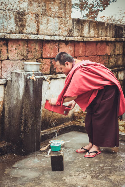Monk washing dishes near Kurjey Lhakhang (Temple of Imprints) in Bumthang valley, Bhutan stock photo