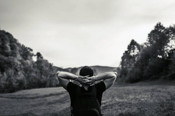 Young tourist man in the mountains with sky and forest on background, black and white