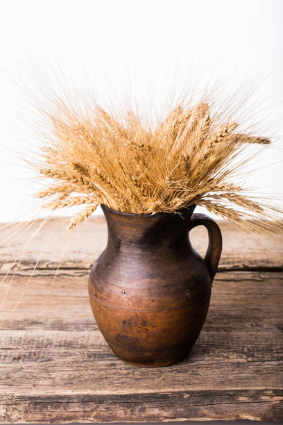 istock Rye spikelets in old pot on wooden background 875383852