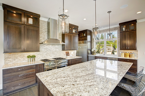 Luxury kitchen accented with large granite kitchen island, taupe tile backsplash, natural brown wood cabinets and lots of natural light. Northwest, USA
