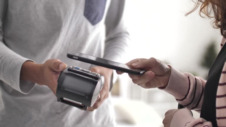 People using Contactless Payment with Mobile Phone in a shop, Clothing store, Close-up