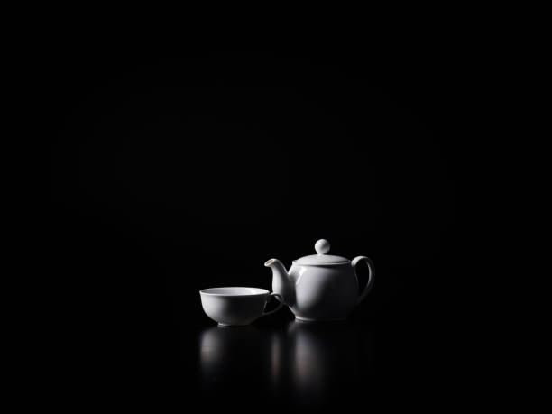 istock Cup of hot tea and teapot on the black background 875405576