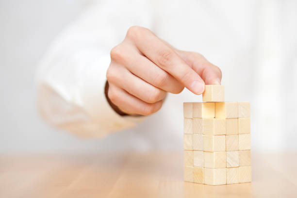 istock Man's hand adding the last missing wooden block into place. Business success concept. 875408730
