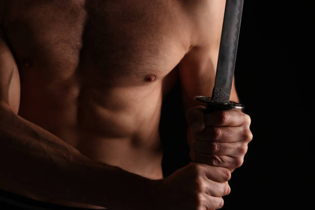 istock Strong muscular man holding a katana sword close up. 875413050