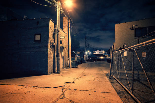 scary dark city chicago alley next to an urban warehouse and parking lot. - street light parking lot night lot imagens e fotografias de stock