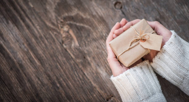 istock Hands and gift box for holiday over wooden background with copy space 875420260