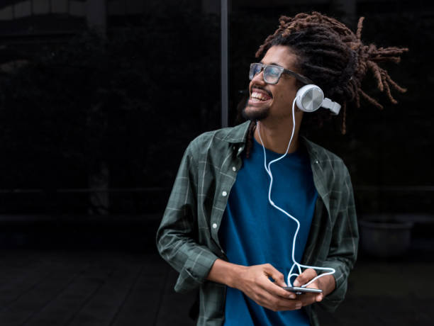 bel uomo nero che ascolta musica e ride mentre ascolta un audiolibri - mid adult audio foto e immagini stock