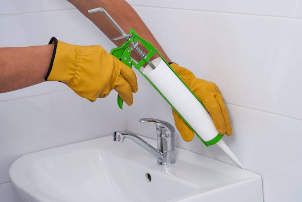 sanitary silicone sealant plumber fills the seam between the sink and the tile with a silicone sealant sealant photos stock pictures, royalty-free photos & images