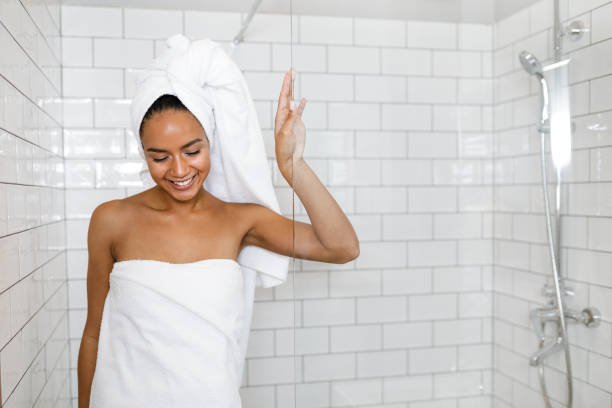 jonge vrouw in witte handdoeken gewikkeld rond het hoofd en het lichaam na de douche - douche stockfoto's en -beelden