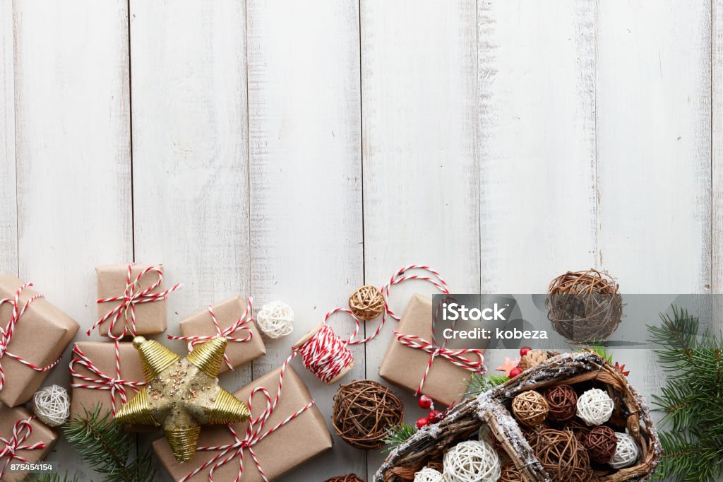 Christmas white background with toys, decorations and gift boxes Christmas toys, decorations, presents and gift boxes wrapped in kraft paper on white wooden background, copy space Backgrounds Stock Photo