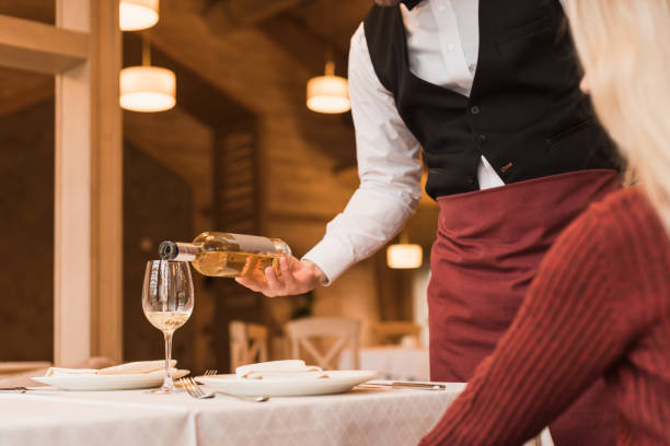 Waiter pouring wine into glass