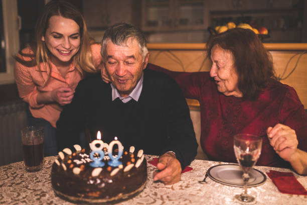 дедушка празднует день рождения с семьей дома - кусок торта фотографии стоковые фото и изображения