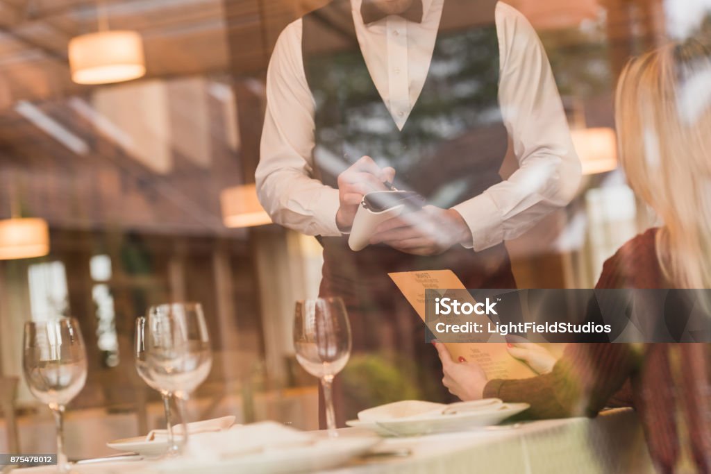 Waiter writing down the order of customer Cropped image through window of Waiter writing down the order of customer at the restaurant Waiter Stock Photo