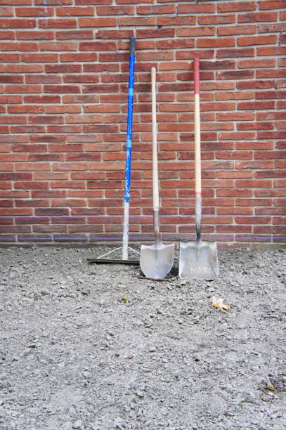 istock Come Along Rake and Two Shovels Against Red Brick 875490568