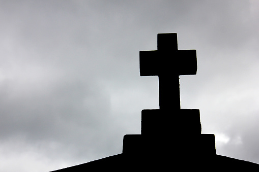 Cross silhouetted against a cloudy sky