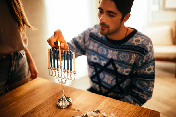 青年は、ユダヤ人 hannukah の本枝の燭台にろうそくを照明 - menorah hanukkah candle human hand ストックフォトと画像