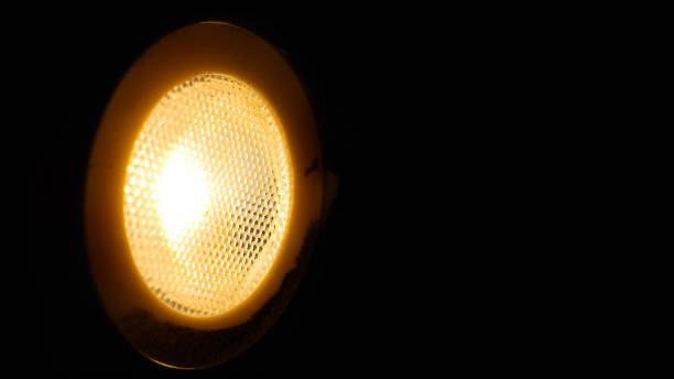 istock Macro yellow LED spotlight round glass grid cover, in dark black background, widescreen 875503120