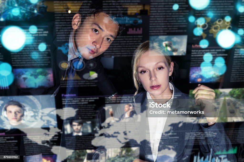 Two business persons in front of futuristic display. Graphical User Interface(GUI). Head up Display(HUD). Internet of things. Journalist Stock Photo