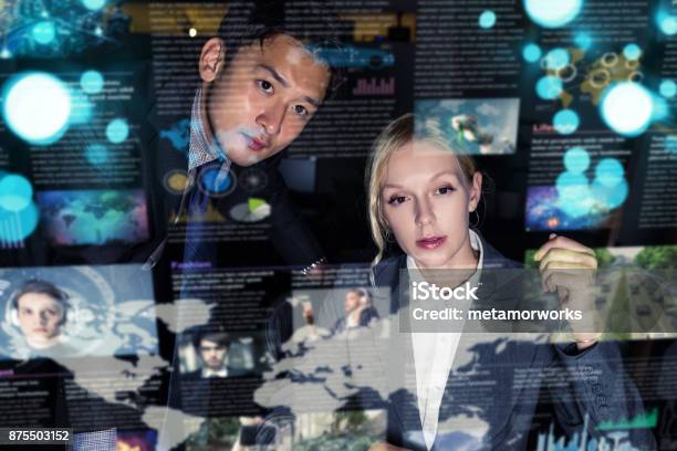 Two Business Persons In Front Of Futuristic Display Graphical User Interface Internet Of Things Stock Photo - Download Image Now