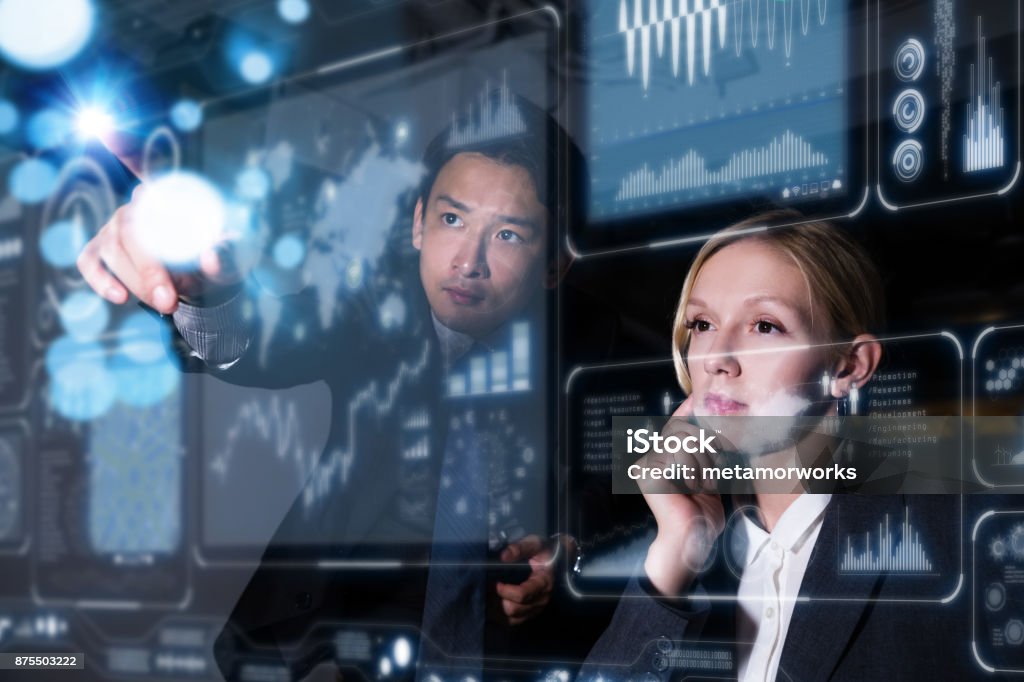 Two business persons in front of futuristic display. Graphical User Interface(GUI). Head up Display(HUD). Internet of things. People Stock Photo