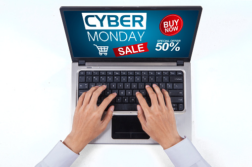 Top view of unknown businessman's hand typing on a computer with Cyber Monday Sale text on the screen, isolated on white background