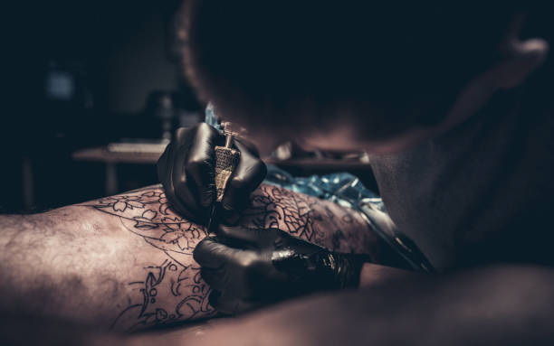 istock Tattoo master making tattoo on customer's leg 875514846