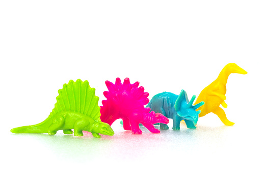 Small colorful dinosaur toy on white background in a row
