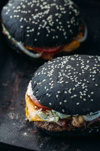 istock Black burger with meat, cheddar cheese and vegetables. Rustic style 875518352