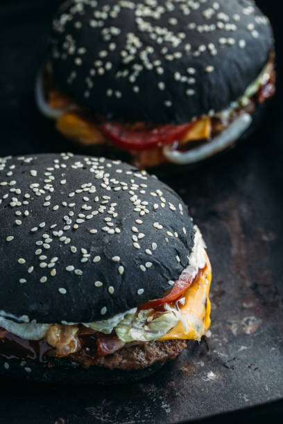 istock Black burger with meat, cheddar cheese and vegetables. Rustic style 875518392