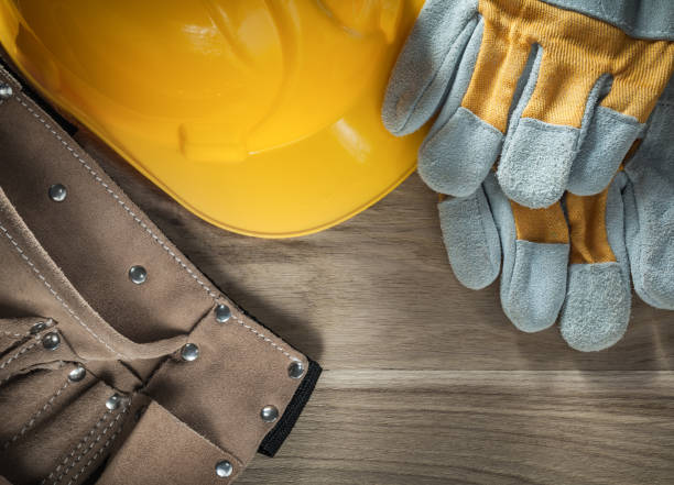 istock Leather tool belt safety gloves hard hat on wooden board 875527762