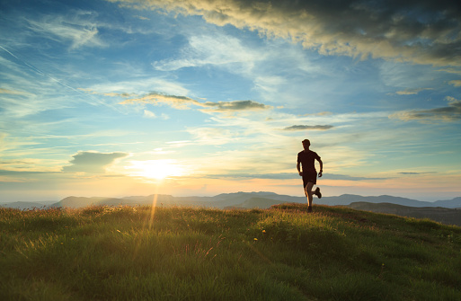 Athlete trailrunning in the mountains during a nice sunset. With motionblur.