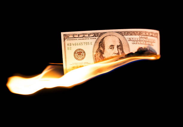 istock a hundred dollars burn in a fire on a black background 875552968