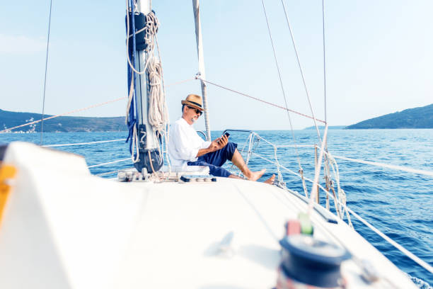 istock Man on a luxury yacht looking at a smartphone 875554748