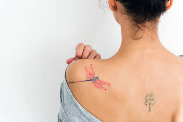 una mujer muestra su tatuaje en la espalda - tattoo women back rear view fotografías e imágenes de stock