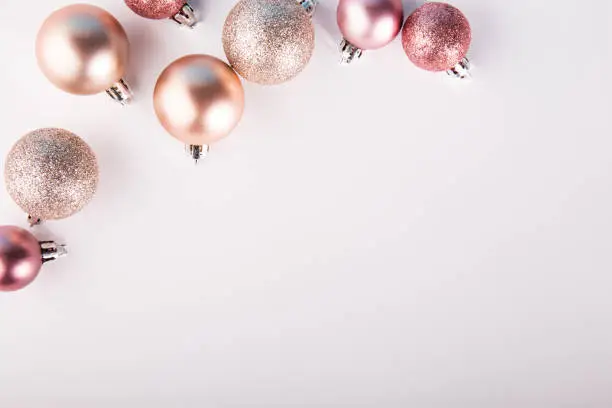 Photo of From above shot of glittering pink baubles lying on white background.