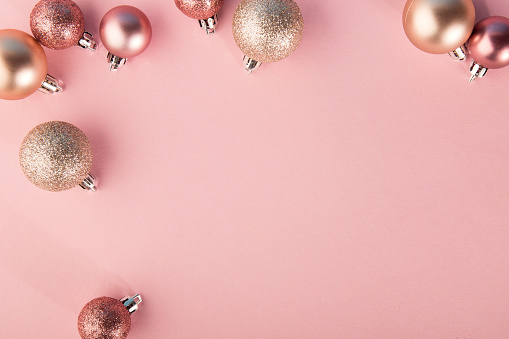 From above shot of bright glittering baubles composed in row on pink background.