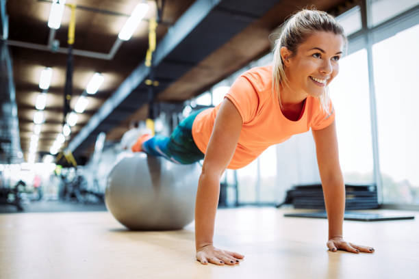 Young attractive woman doing push ups using ball Young attractive woman doing push ups using ball in gym fitness ball photos stock pictures, royalty-free photos & images