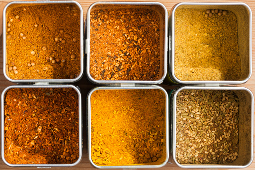 Six different spice mixtures in metal cans seen from above