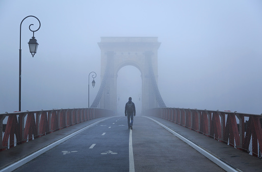 Person walking on a bridge on a foggy December day. Pont Masaryk, Lyon, France.