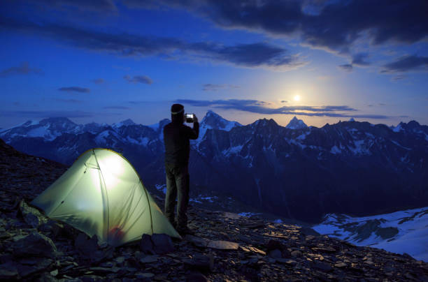 Matterhorn view Mountaineer taking a photo with his smartphone of the moon rising above the famous Matterhorn mountain, Switzerland. tent photos stock pictures, royalty-free photos & images