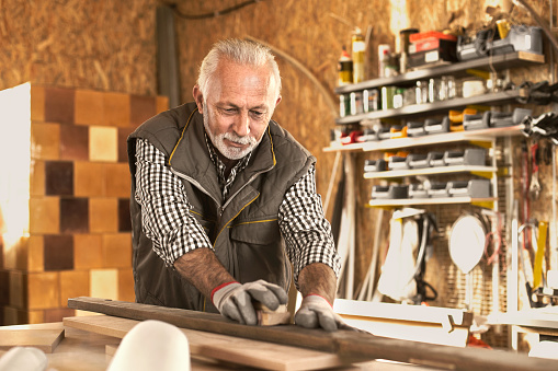 Carpenter Worker Sanding Wooden Table with Sander in workshop